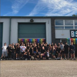 A photograph of 30+ people standing outside BYS Crossfit as part of their fundraising event for Switchboard. There are rainbow streamers behind them.